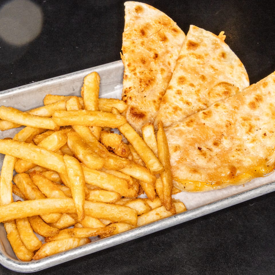 Golden grilled quesadilla wedges served with crispy French fries in a metal tray.