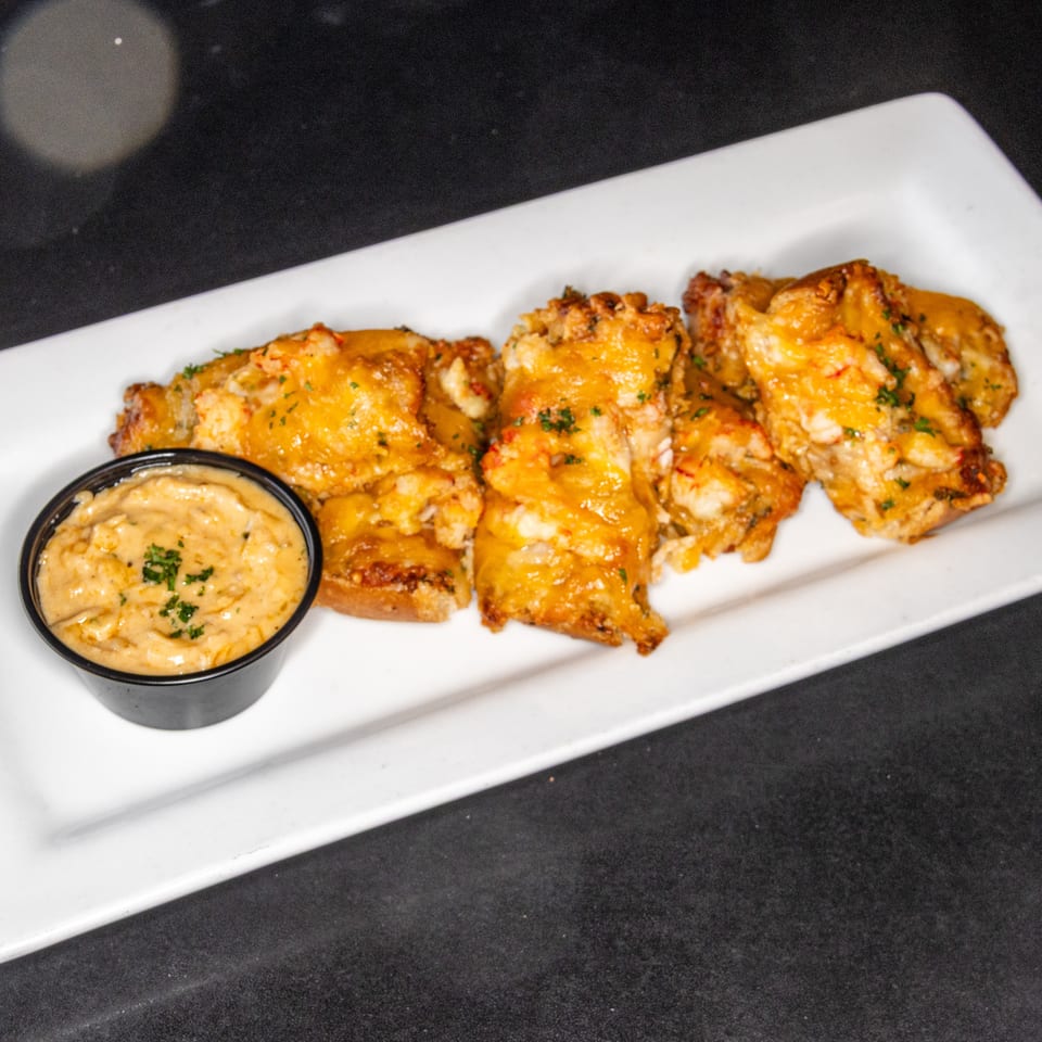 Golden-brown baked chicken wings topped with herbs, served on a white platter with creamy dipping sauce.
